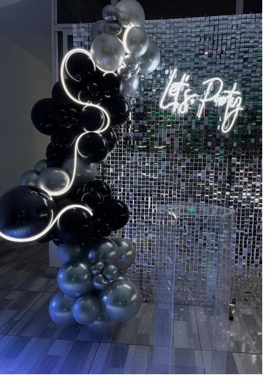 Salón con pared de espejos dorados y arco de globos en tono vino